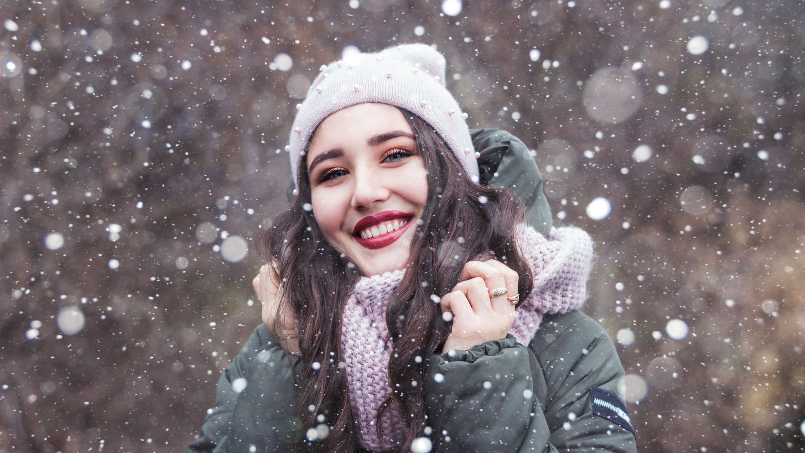 Frau mit Mütze und Schal im Schneefall
