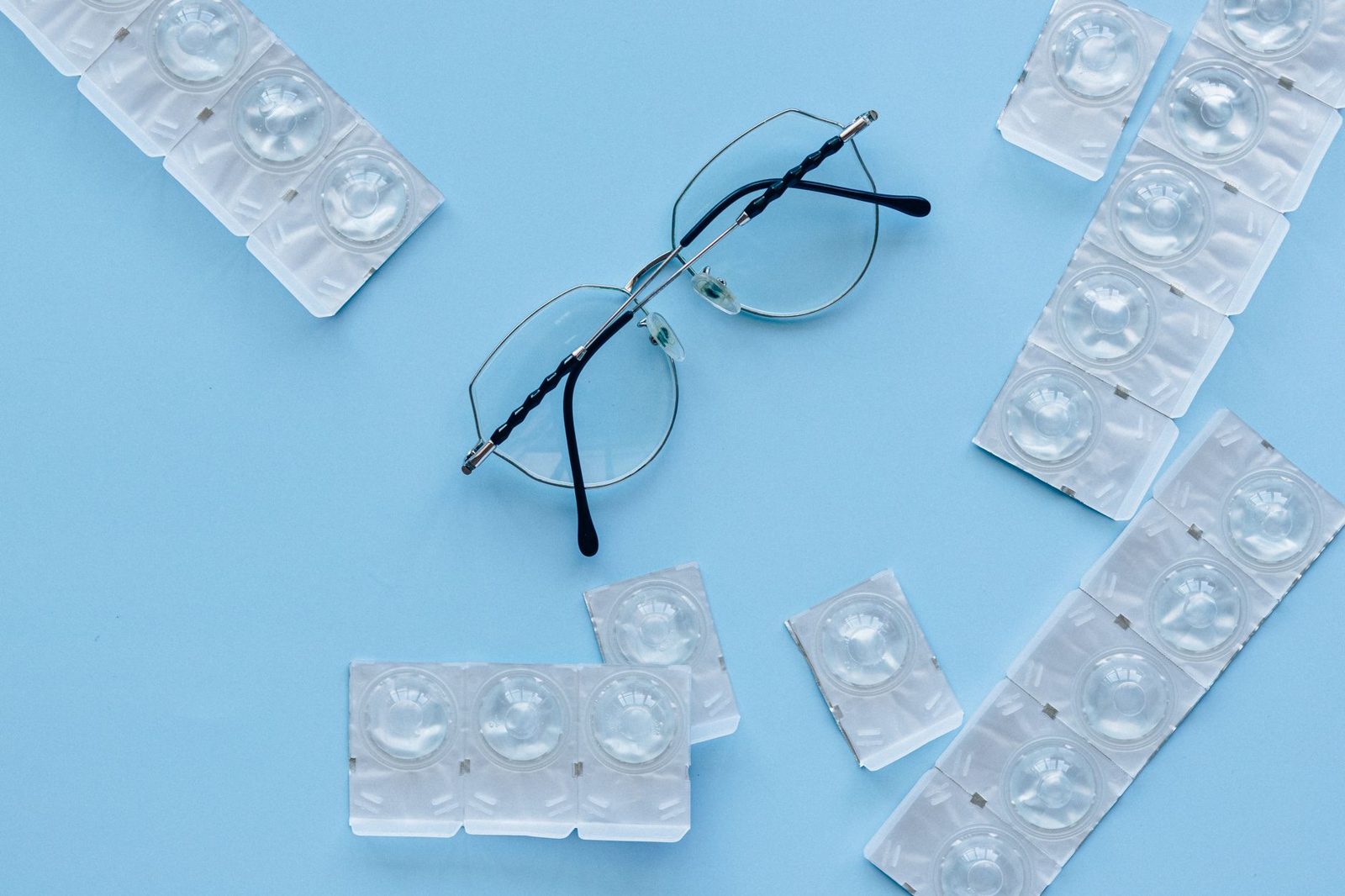 Kontaktlinsen in Blisterverpackungen neben einer Brille