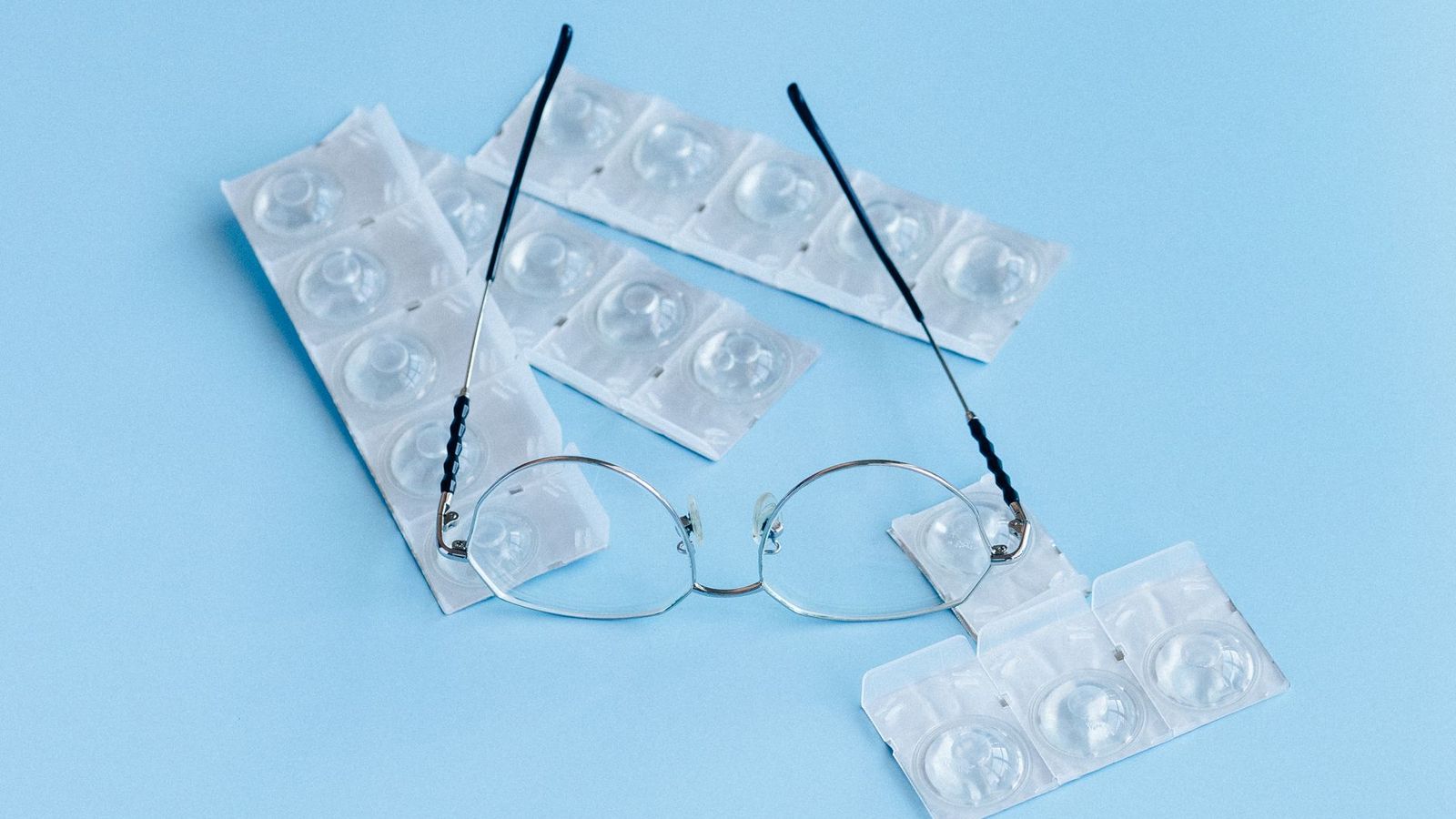 Blisterpackungen von Tageslinsen neben einer Brille